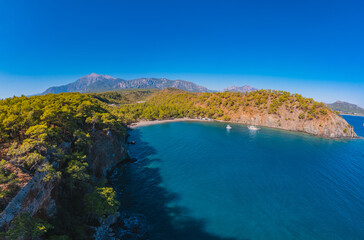 Aerial view Quiet blue lagoon with clear turquoise water and white yacht against backdrop mountains of Turkey