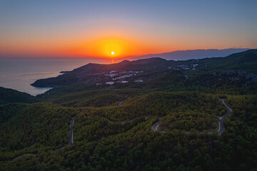 Aerial top view winding road in middle forest background sea Turkey sunset light