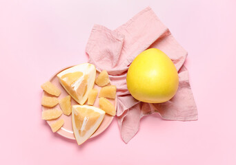 Plate with pomelo fruit and slices on pink background
