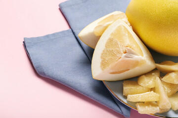 Plate with pomelo fruit and slices on pink background, closeup