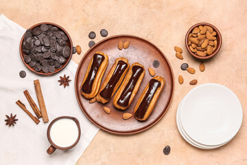 Composition with plate of tasty eclairs, milk, chocolate drops and almond nuts on color background