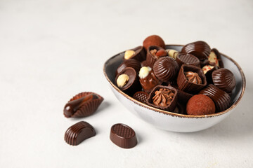 Bowl with chocolate candies on white background