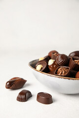 Bowl with chocolate candies on white background