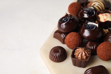 Board with chocolate candies on white background