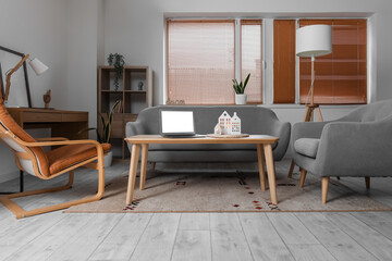 Interior of living room with armchairs, candle holders and laptop