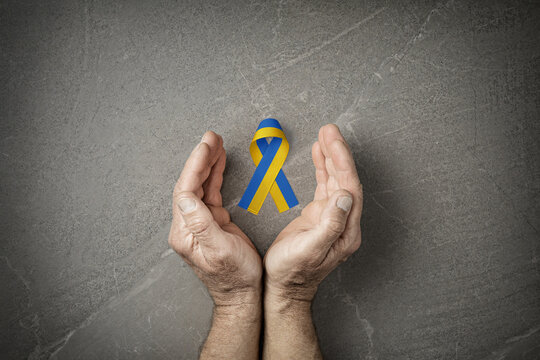 hands with blue and yellow ribbon on marble