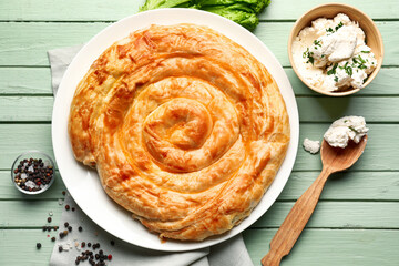 Plate with delicious cheese pie on green wooden table