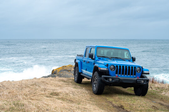 St. John's, Newfoundland, Canada, August 2022: A vibrant blue Jeep Gladiator Rubicon truck 4x4 off road and parked on an old airport runway. The vehicle is covered in dust and dirt from off-roading 
