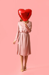 Young woman with balloon for Valentine's Day on pink background