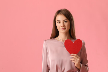 Young woman with paper heart for Valentine's Day on pink background