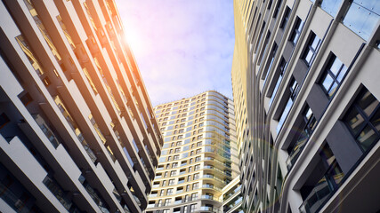 The narrow passage between modern residential buildings. Walls of high-rise apartment buildings and a narrow strip of sky between them. Modern urban living districts. Bottom view.
