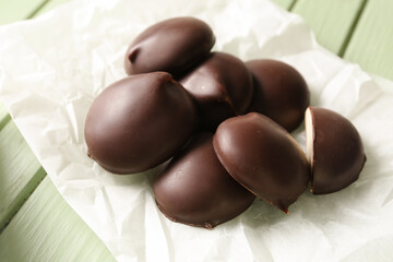 Parchment with delicious bird's milk candies on green wooden background, closeup