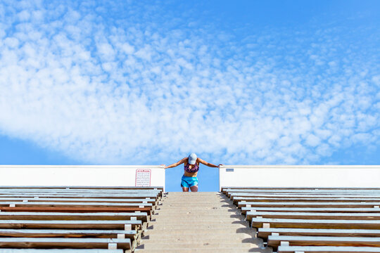 Woman Bending Forward On Top Row Of Stadium