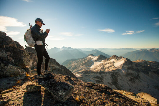 An ultralight backpacker sends a safety message from his smartphone while hiking high in the mountains near Whistler, BC, Canada.