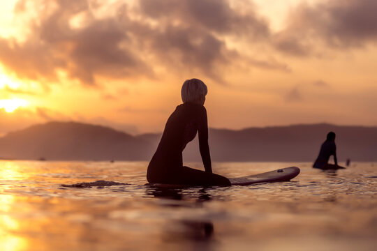 Female surfer in sea at sunset