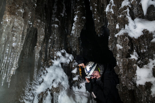 A young man takes a survey reading with compass and clinometer in an ice cave in Larsbreen, Svalbard.