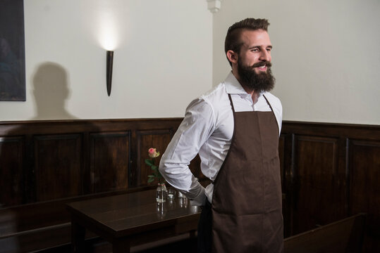 Contemplative smiling manager standing by table at restaurant