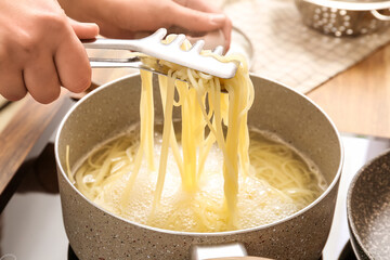 Woman preparing delicious pasta in kitchen, closeup