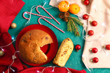 Cut Panettone with mandarins and Christmas decor on green table, top view