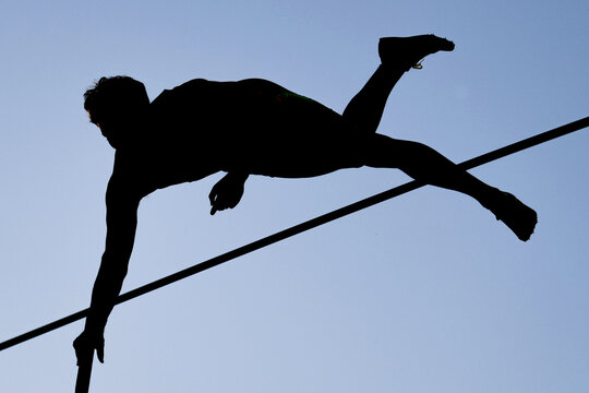 A pole vaulter (silhouette) jumping 