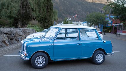 A classic vintage car parked on a street. An old antique blue mini car.