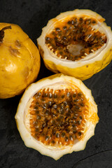 Passion fruit, whole and sliced, on black stone table