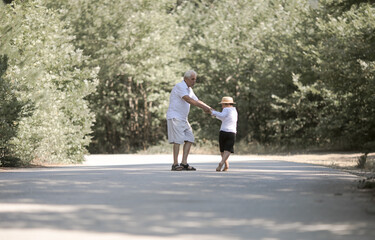 Back view of grandfather and grandson with hat walking on nature
