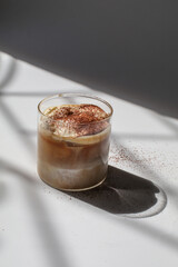 Iced coffee latte on white background under early morning sun light. Morning breakfast minimal concept.