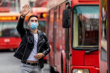 A young man with a protective mask on his face runs to get on the bus