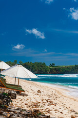 Weißer tropischer Sandstrand mit strahlend blauen Meer und einer Felsen im Hintergrund, Indonesien, Bali