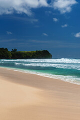 Weißer tropischer Sandstrand mit strahlend blauen Meer und einer Felsen im Hintergrund, Indonesien, Bali