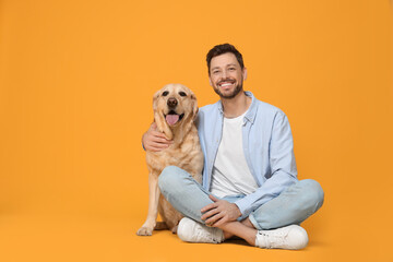 Happy man with his cute Labrador Retriever on yellow background. Space for text