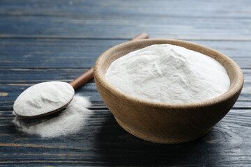 Baking soda in bowl on blue wooden table