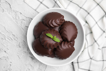 Delicious chocolate covered zephyrs with mint in bowl on light grey background, top view