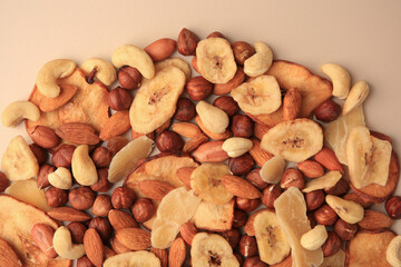 Different tasty nuts and dried fruits on beige background, flat lay