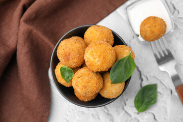 Bowl of delicious fried tofu balls with basil on white textured table, flat lay