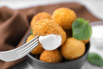 Taking delicious fried tofu ball with sauce from bowl, closeup