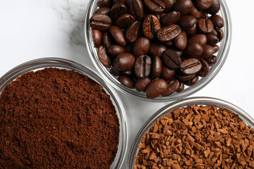 Bowls of beans, instant and ground coffee on white marble table, flat lay