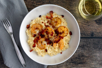 Creamy Shrimp Risotto with Bacon With a Glass of White Wine From Above: A decadent dish made with shellfish, rice, and creamy cheese
