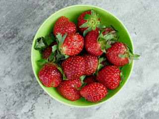 top view of Strawberries in a green bowl on a gray stone background