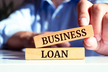 Closeup on businessman holding a wooden block with BUSINESS LOAN message, business concept