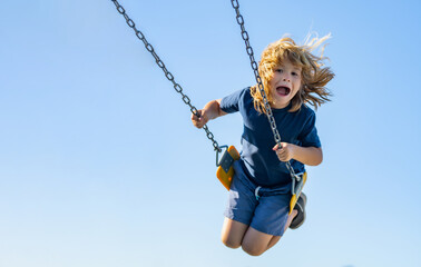 Swinging on playground. Funny kid on swing. Little boy swinging on playground. Happy cute excited...