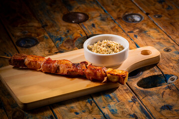 Espetinho de churrasco com farofa em tábua de madeira