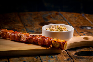 Espetinho de churrasco com farofa em tábua de madeira