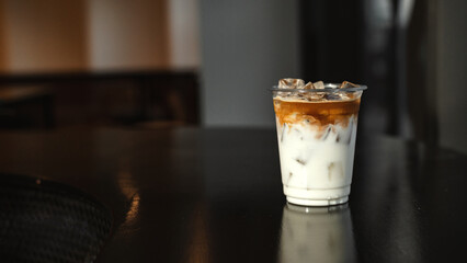 ice latte coffee in plastic glass on black table at cafe​