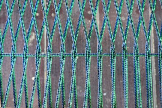 Close up of fishing net with blue and green ropes on wooden background
