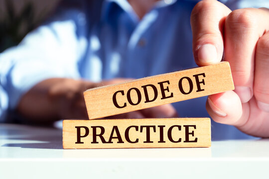 Closeup on businessman holding a wooden block with CODE OF PRACTICE message, business concept
