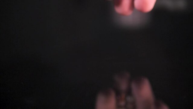 The man drops pills from his hand, enzyme, pancreatic treatment. Close-up shot on a black surface. Slowmotion.