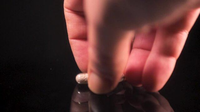 The man picks up pills from the table, enzyme, pancreatic treatment. Close-up shot on a black surface. Slowmotion. Scene A.