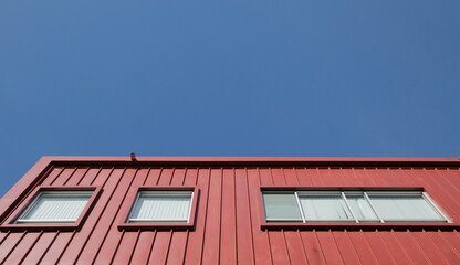 Rectangular windows on red building facade against blue sky